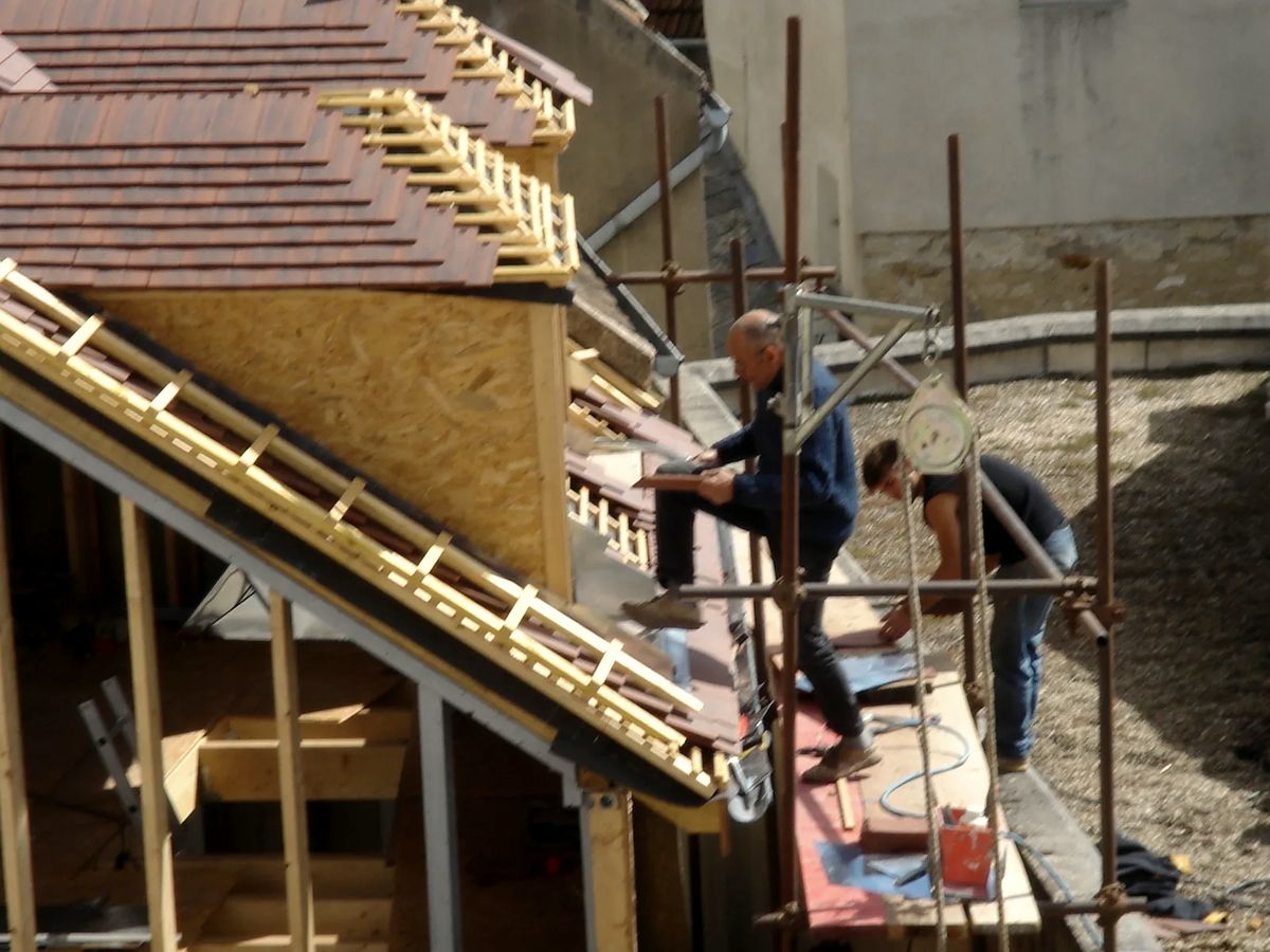 Couvreurs au travail sur la pente d'une toiture en rénovation