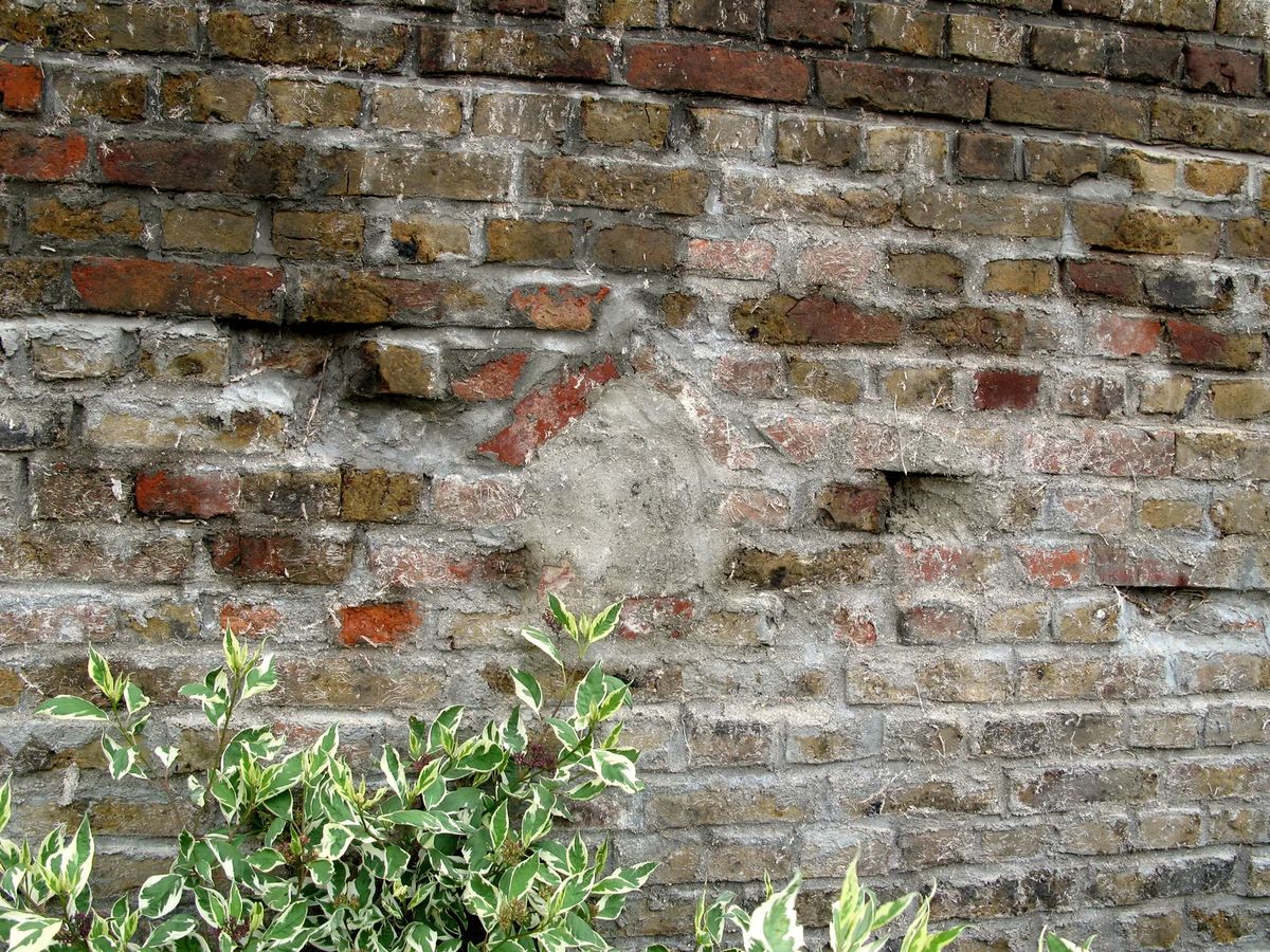 Mur en briques anciennes avec une niche rebouchée au mortier