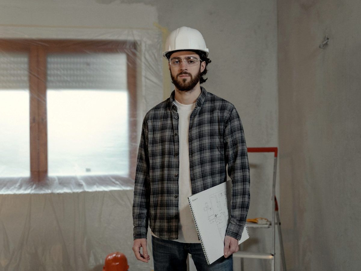 Homme consultant des plans dans une pièce en cours de rénovation