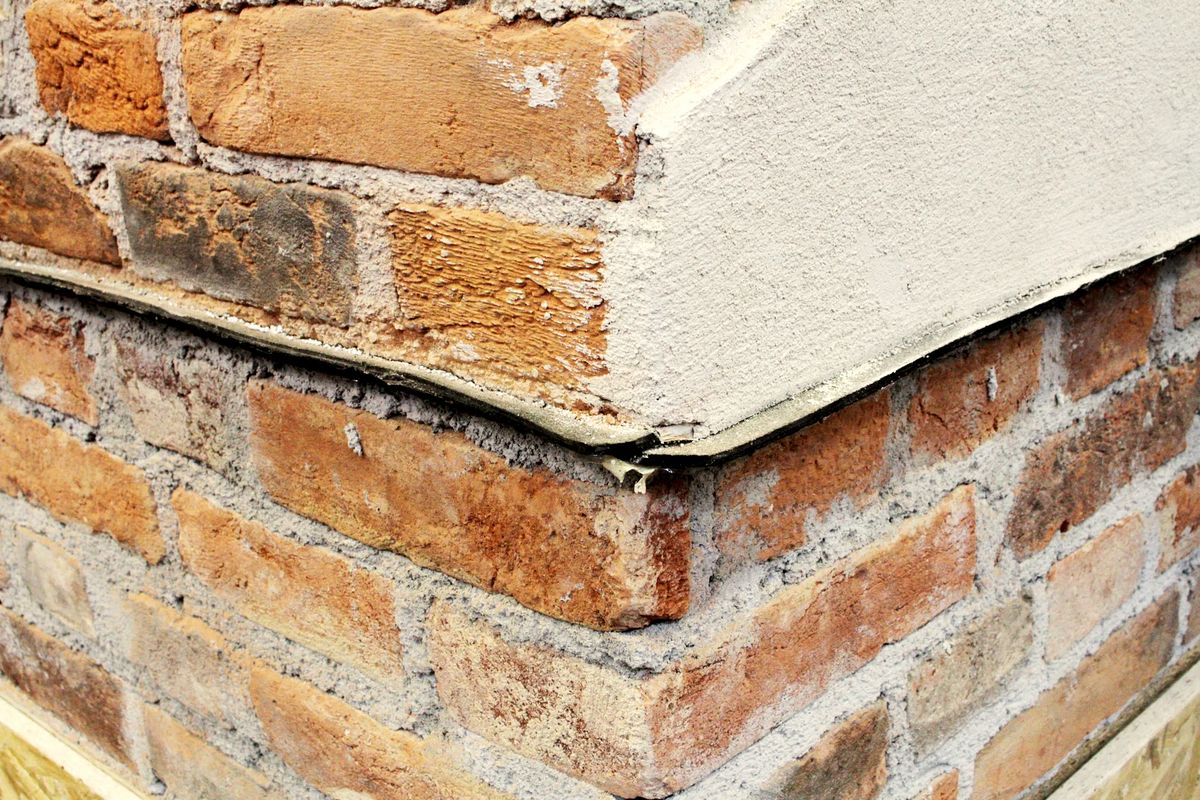 Membrane noire d'étanchéité horizontale insérée dans la base d'un mur en briques